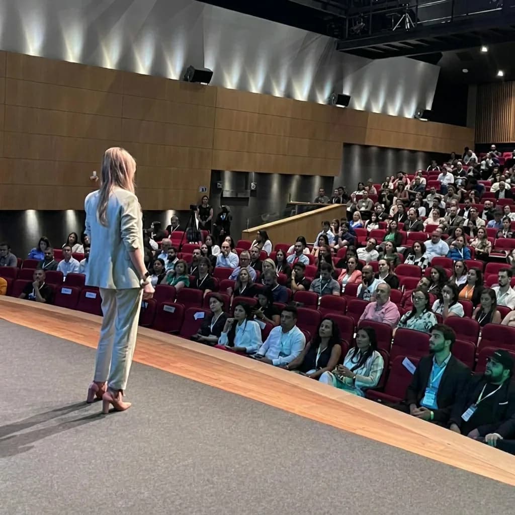 Bell Nacif palestrando para uma plateia em auditório.